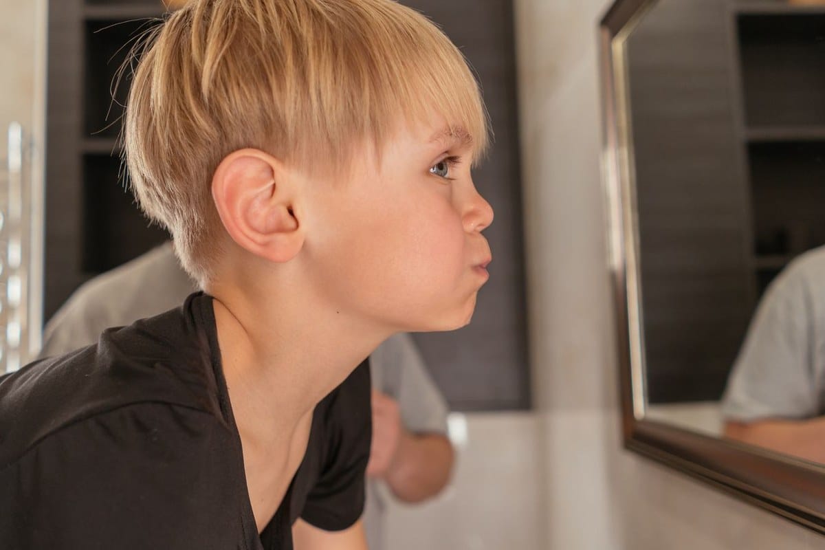 Enfant se regardant les dents dans le miroir de la salle de bain