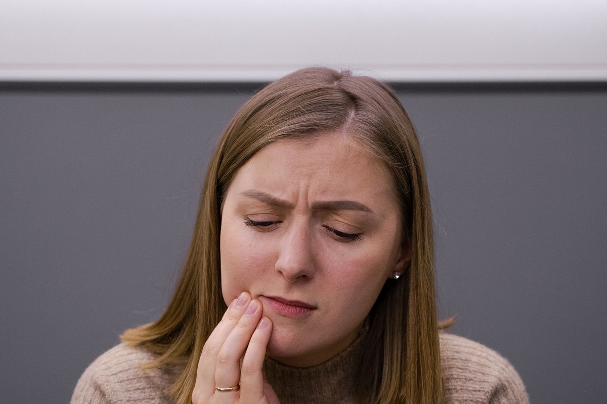 Femme se tenant la joue avec une expression de douleur