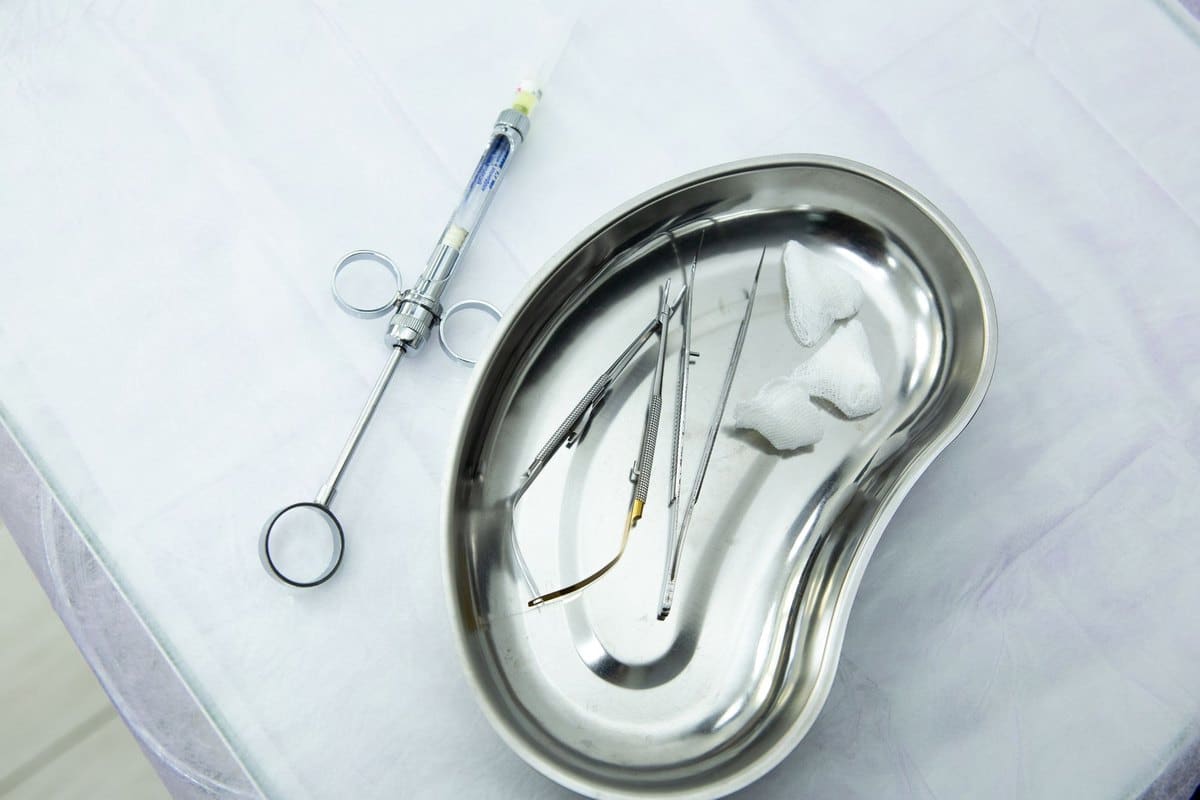 Haricot en inox et seringue dentaire posés sur un champ stérile