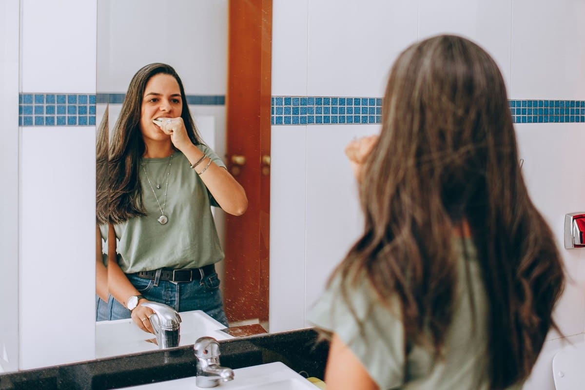 Personne se regardant les dents dans le miroir de la salle de bains